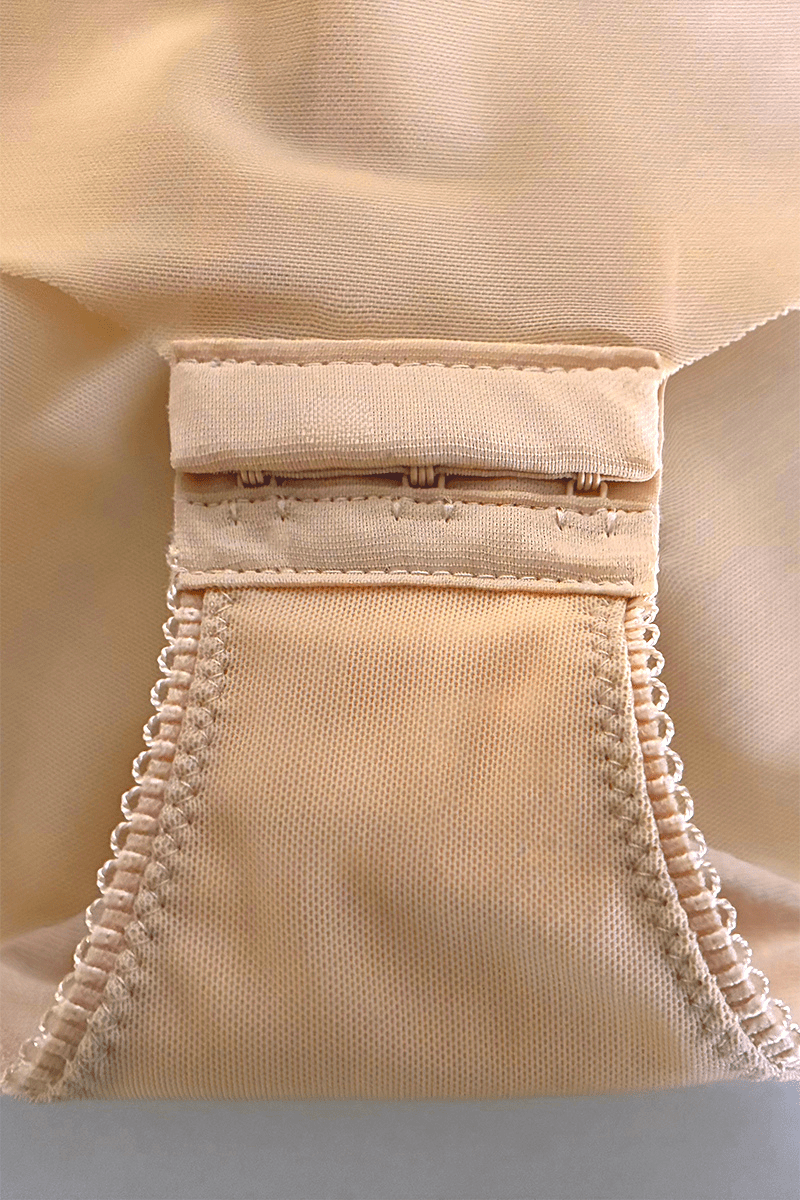 Close-up of the Ender Legard KYA Nude gusset showing the three-position hook-and-eye fastening and surrounding mesh construction.