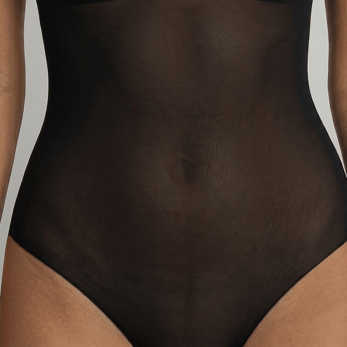 Close-up of the LEXI Black backless bodysuit's sheer power mesh torso panel and the laser-cut edge of the high-leg brief, which sits flat against the skin.