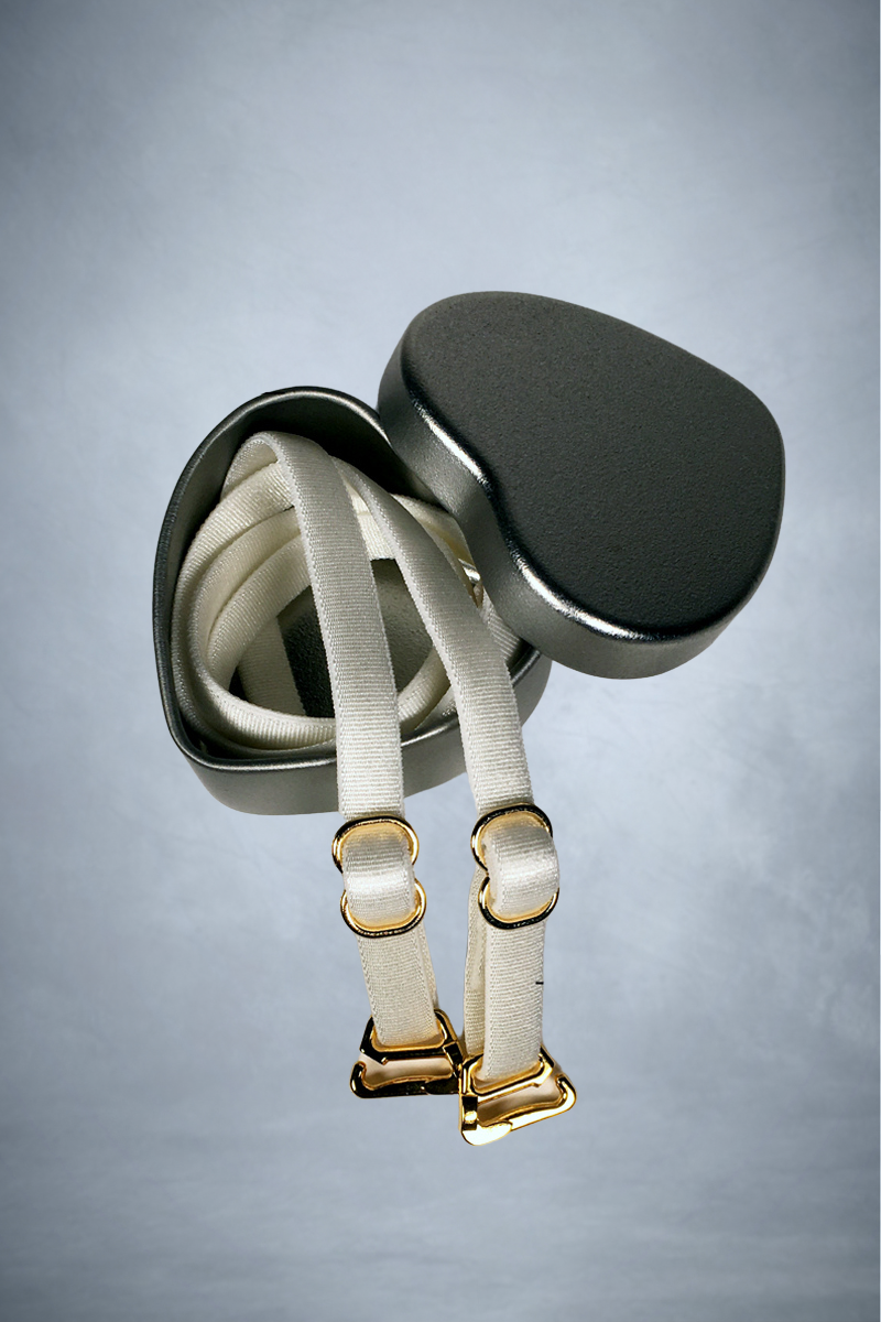 Close-up view of a pair of adjustable spaghetti bra straps in heart-shaped metal presentation tin.