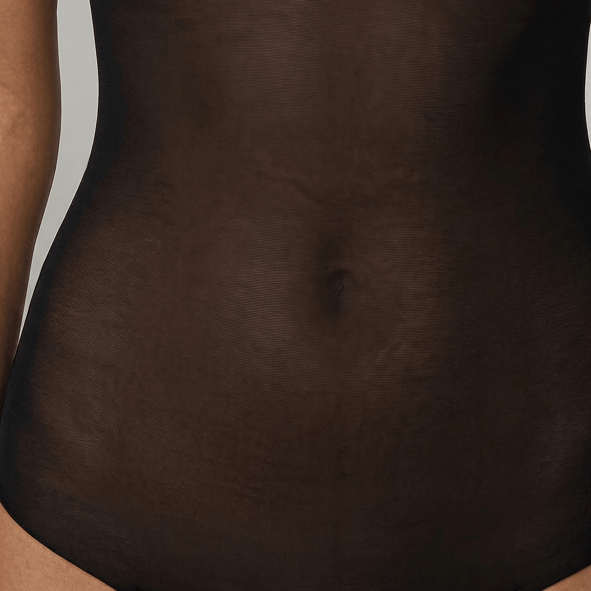 Close-up of the SKYE Black bodysuit's smooth power-mesh coverage across the tummy.
