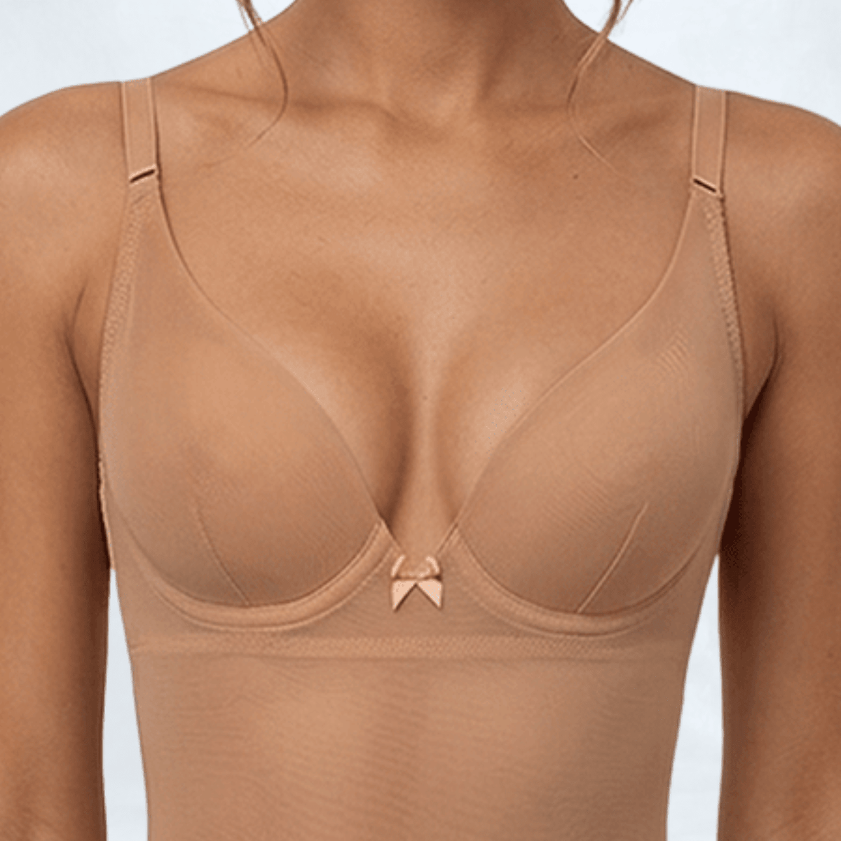 Close-up of the SKYE Nude minimiser cup showing the underwire shape, a fine centre dart seam, and the decorative bow between the cups.