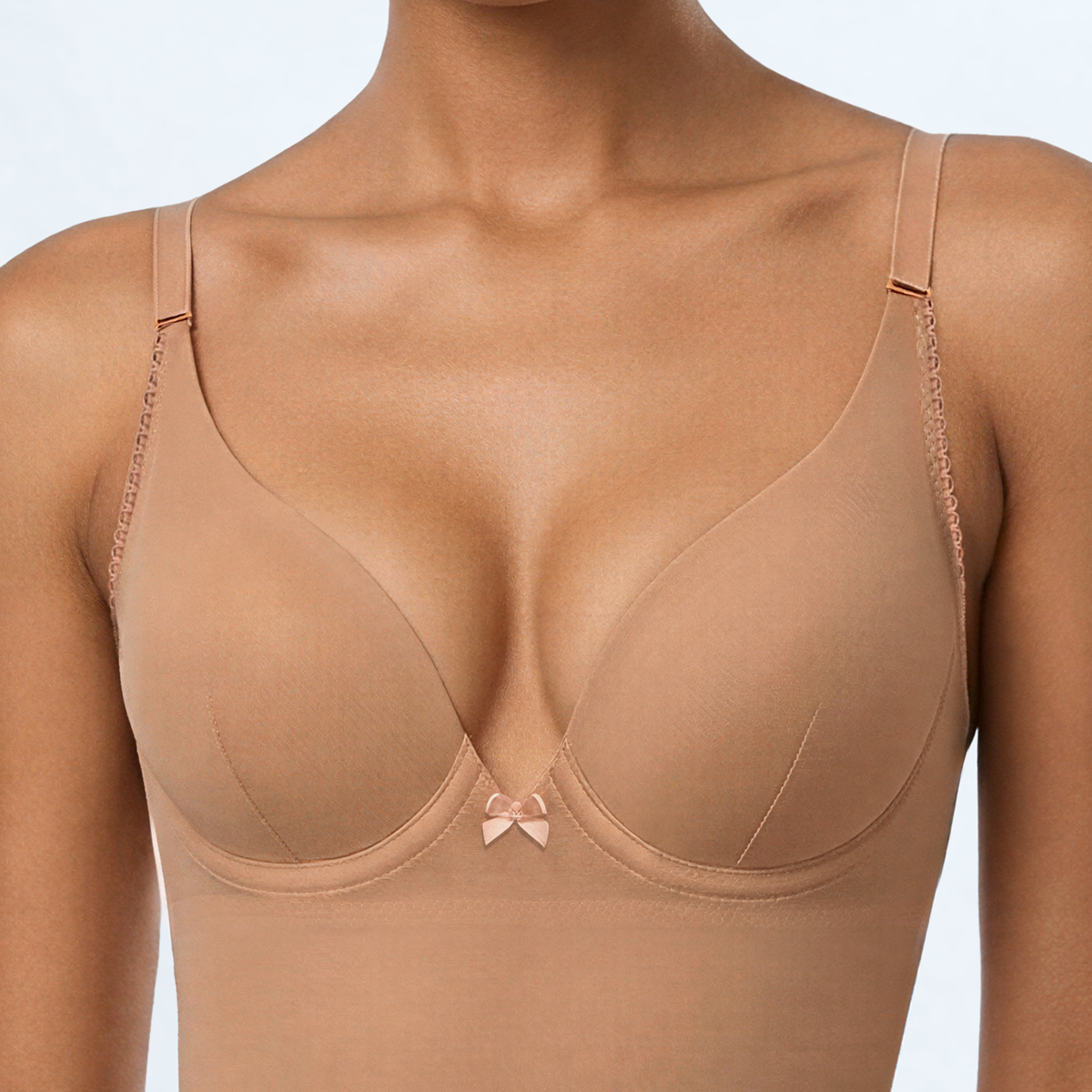 Close-up of the SKYE Nude minimiser cup showing the underwire shape, a fine centre dart seam, and the decorative bow between the cups.