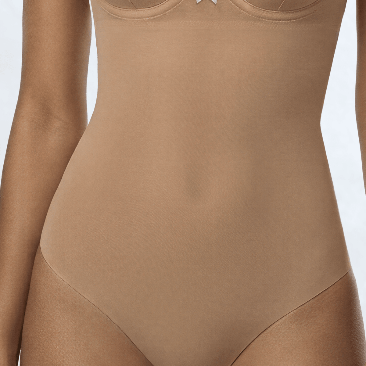 Close-up of the Ender Legard SKYE Nude bodysuit showing the smooth power-mesh front panel across the waist and abdomen, continuing into the tanga briefs with laser-cut edge.