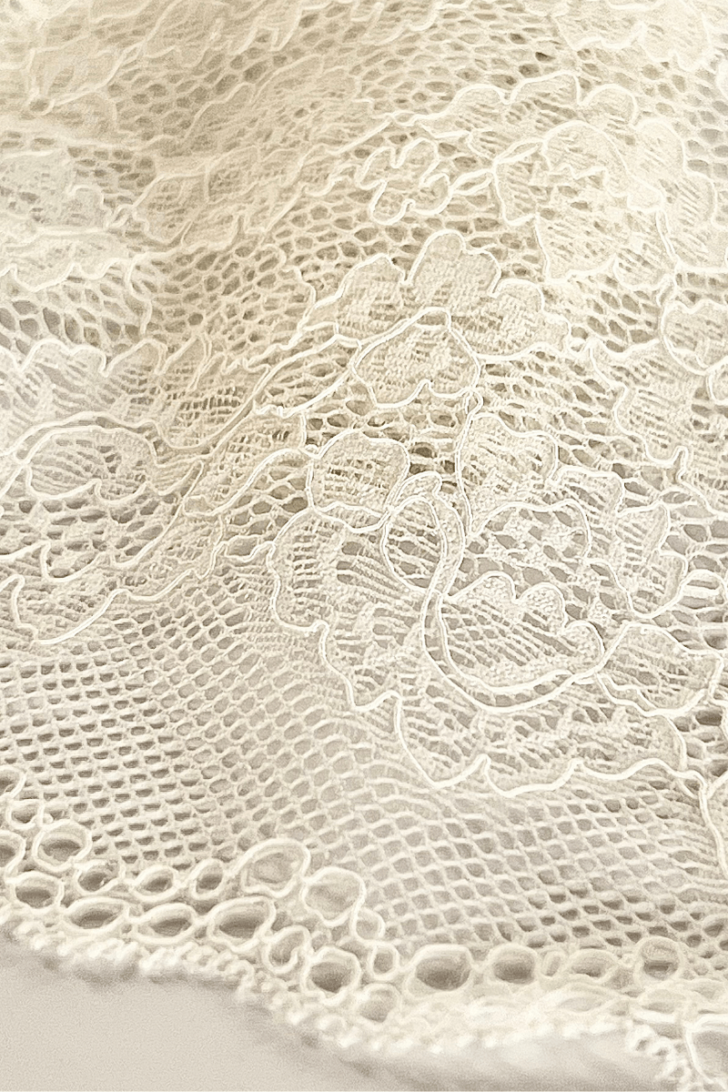 Close-up of the UMA Ivory stretch lace fabric, showing the open floral lace weave and texture.