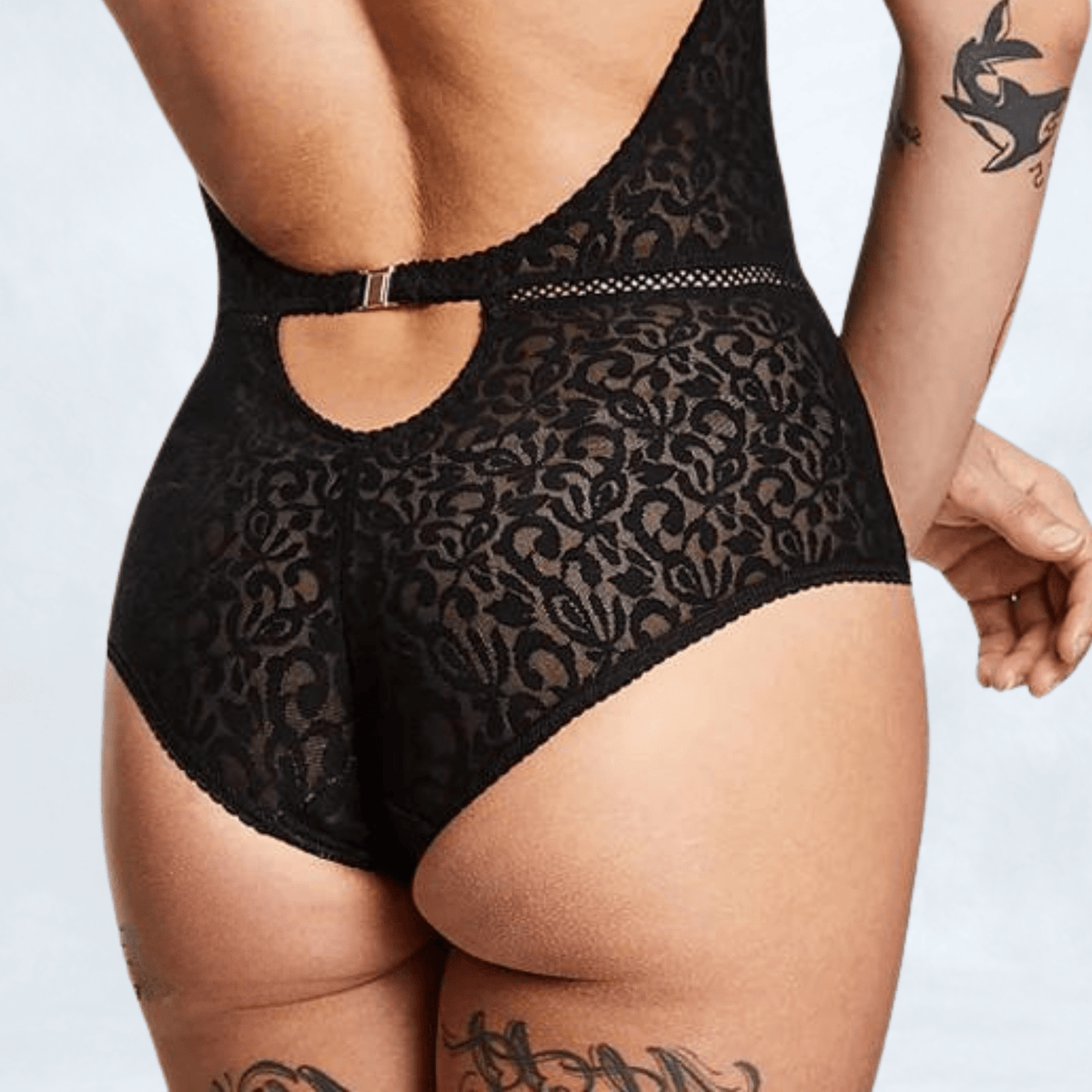 Close-up of the low back, showing the narrow waist-height strap with metal clasp, the keyhole opening below it, and the jacquard full-brief panel.