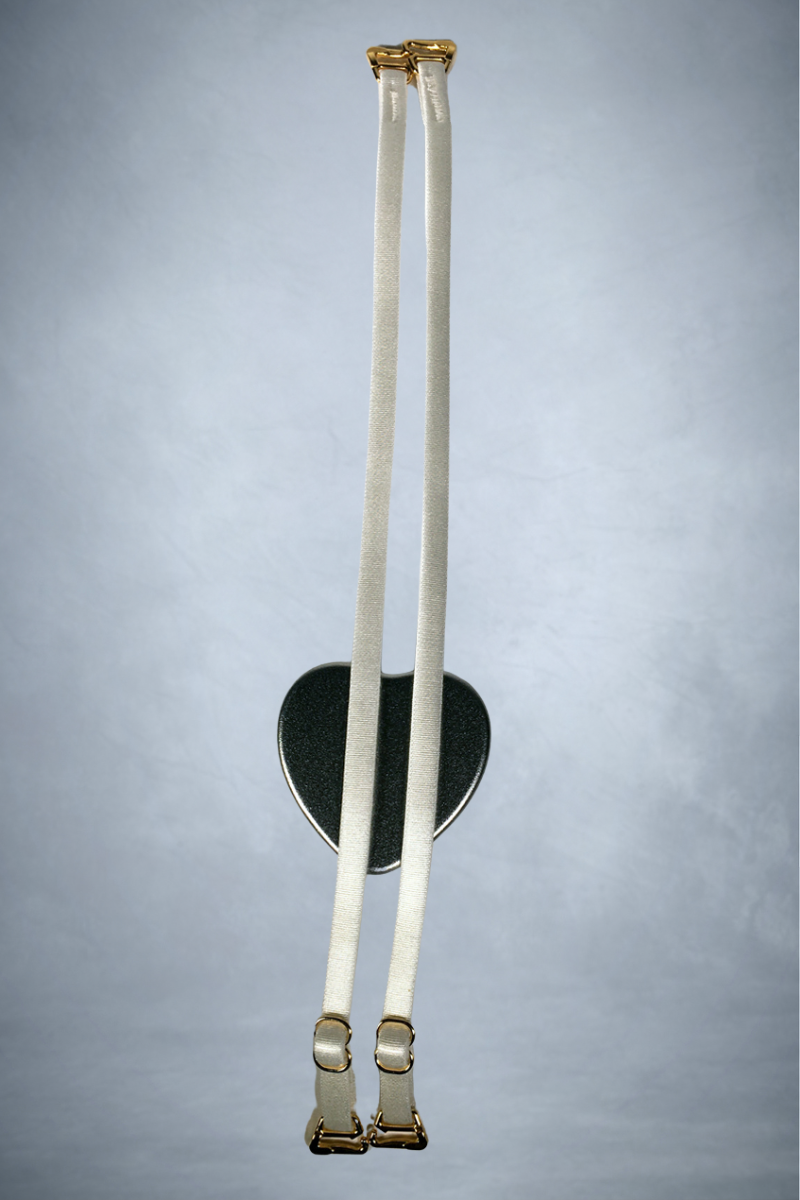 Close up view of a pair of handmade Ender Legard nude coloured spaghetti bra straps with silver presentation tin. 